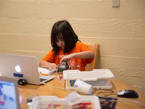 a person sitting at a desk with a laptop and other objects