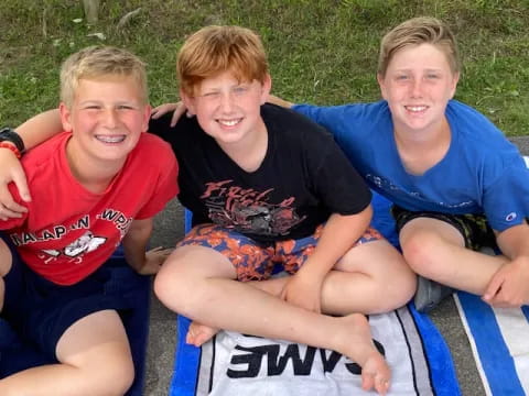 a group of boys sitting on a blanket in the grass
