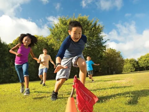 a group of kids running on a grass field