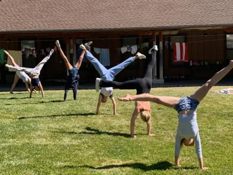 a group of people doing handstands in a grassy field