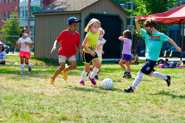 a group of kids compete over a football ball