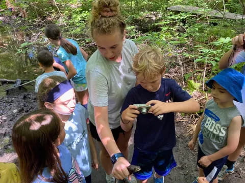 a group of children looking at a person holding a small animal