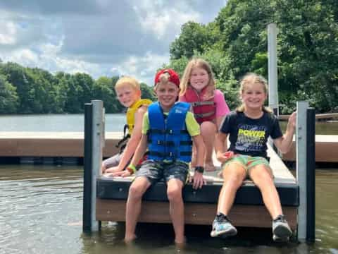 a group of children sitting on a dock