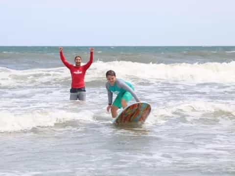 a couple of people stand on surfboards in the ocean