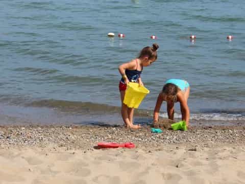 a couple of kids playing in the sand at the beach