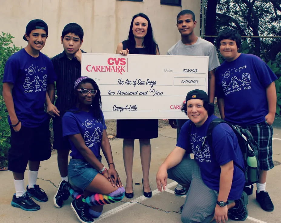 a group of people posing for a photo with a sign