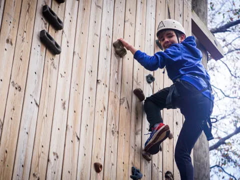 a boy climbing a wooden wall