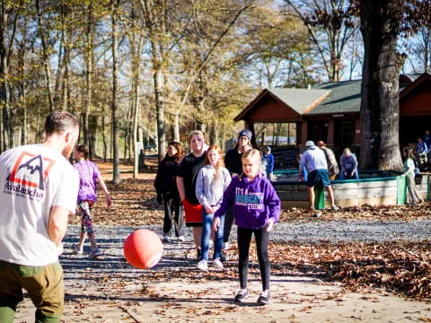 a group of people playing with a ball in a park