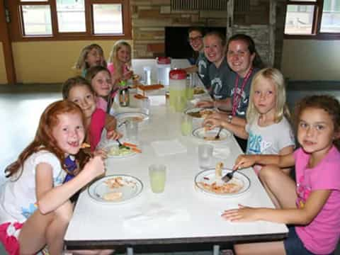 a group of people sitting at a table eating food