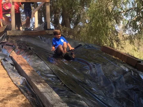 a boy sitting on a log in a stream