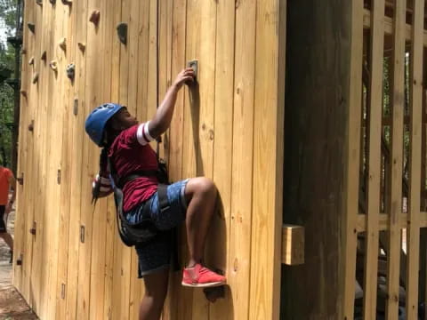 a man climbing a wooden wall