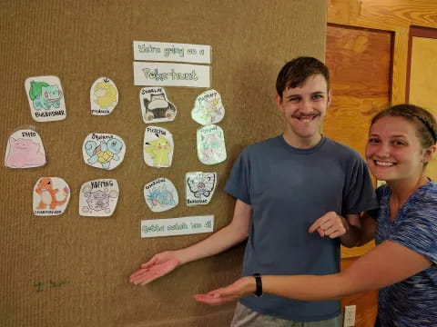 a man and woman posing for a picture with a board with stickers on it