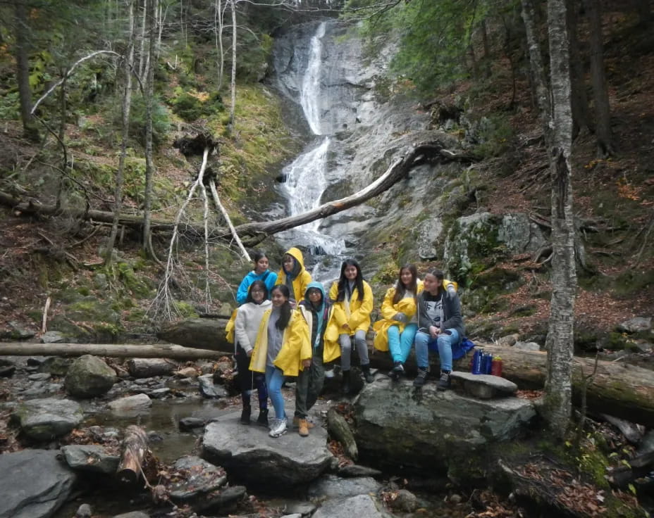 a group of people posing for a photo next to a waterfall