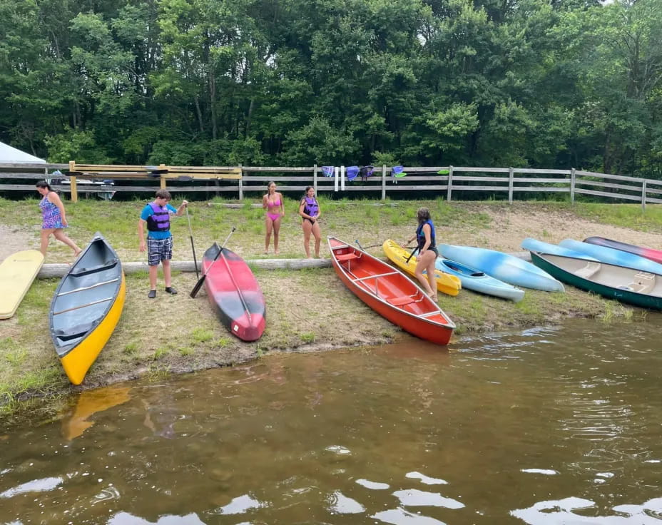 a group of people standing next to kayaks on a river