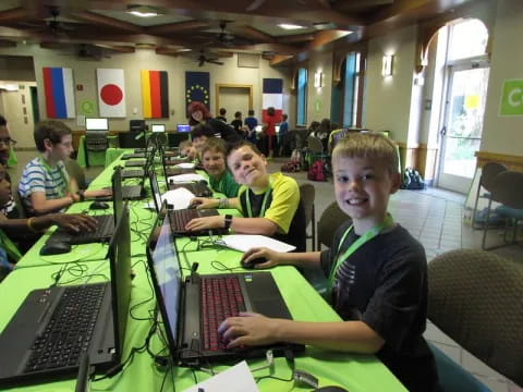 a group of boys sitting at a table with laptops