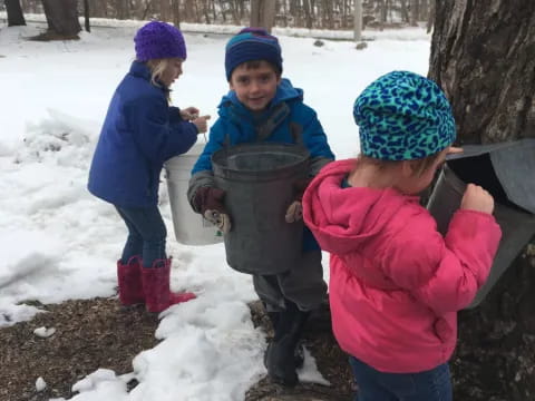 a group of kids holding a large metal object in the snow
