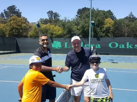 a group of people pose for a photo on a tennis court