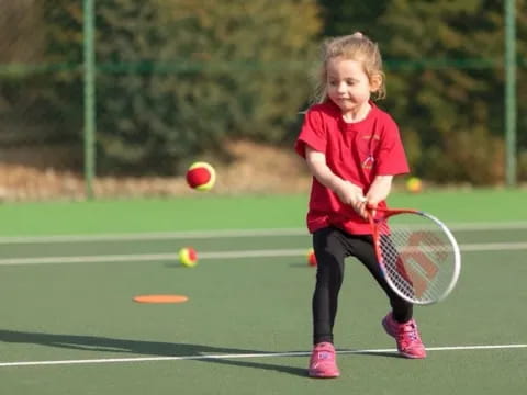 a little girl playing tennis