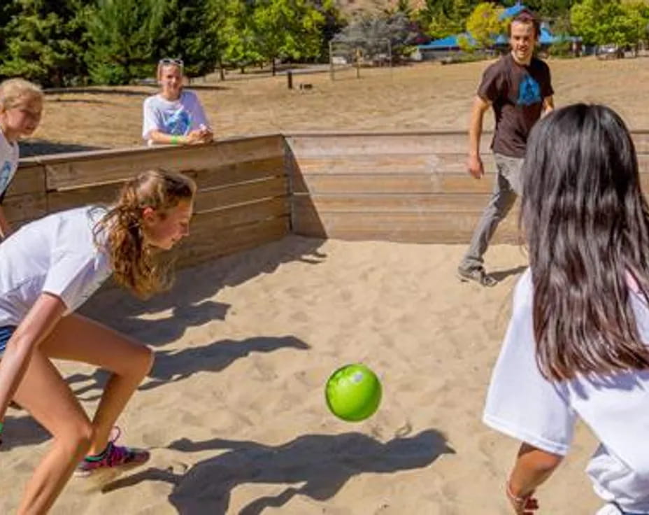 a group of people playing with a ball on a sandy beach