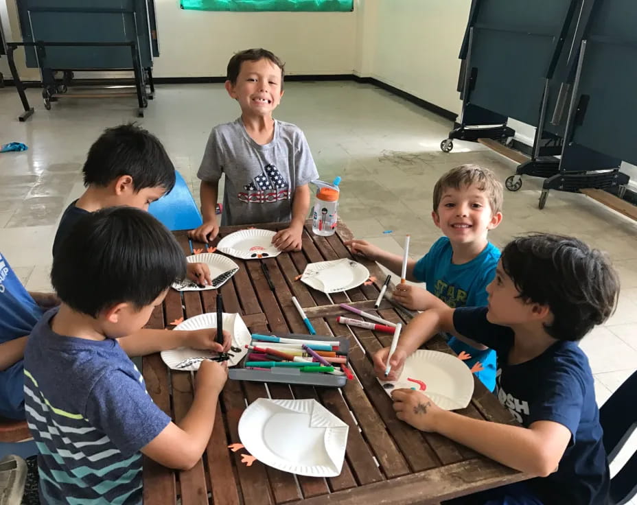 a group of children sitting around a table eating food