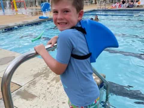 a boy standing by a pool