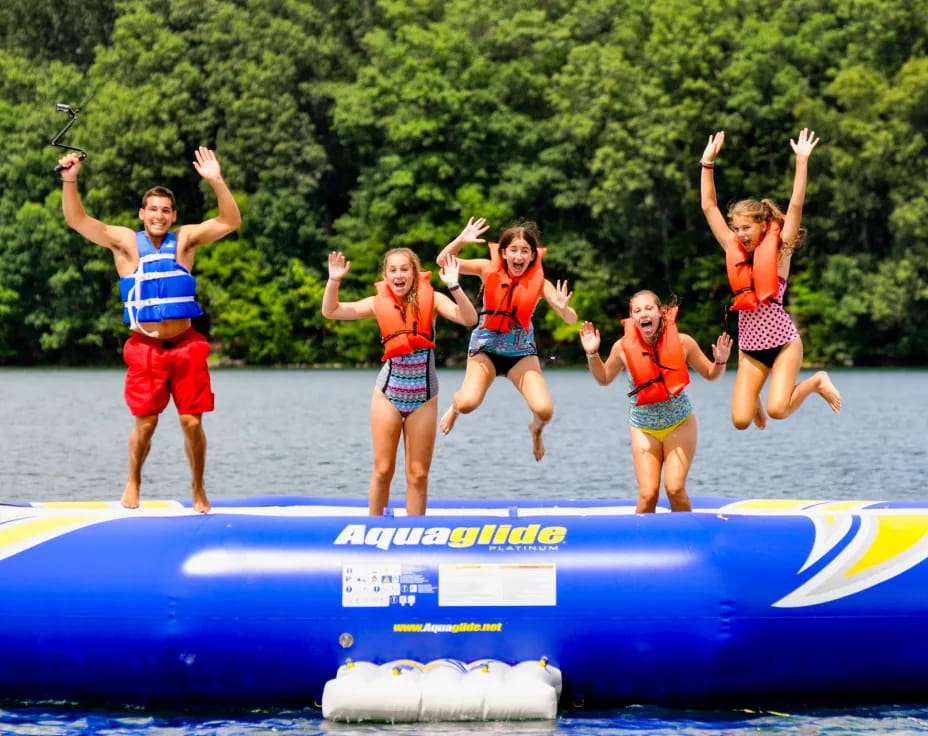 a group of people jumping off a blue raft in the water