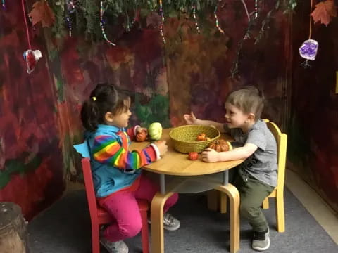 a couple of children sitting at a table eating food