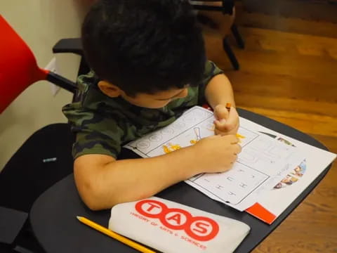 a child sitting at a desk writing on a piece of paper