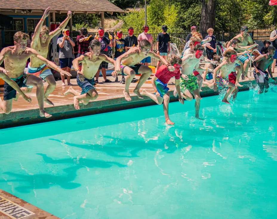 a group of people jumping into a pool