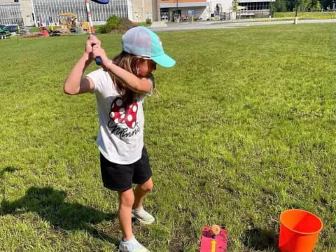 a girl holding a bucket and a bucket in a grass field