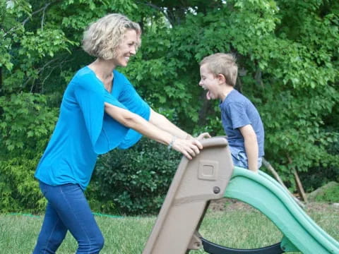 a person and a boy playing on a playground toy