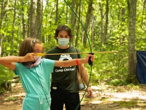 a man and a woman wearing face masks and holding bows and arrows