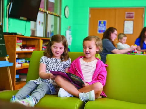 a group of children sitting on a green couch in a classroom