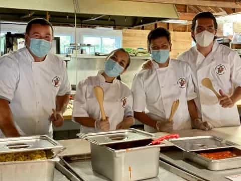 a group of people wearing masks and cooking food in a kitchen