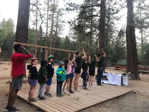 a group of people standing on a wooden deck in the woods