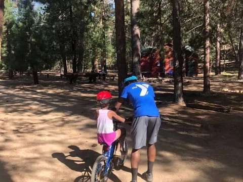 a person and a girl on a bike in the woods