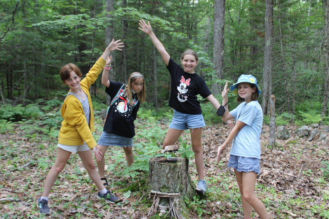 a group of girls posing for a picture in the woods