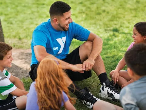 a man kneeling in front of a group of children