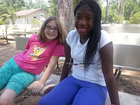 a couple of girls sitting on a bench