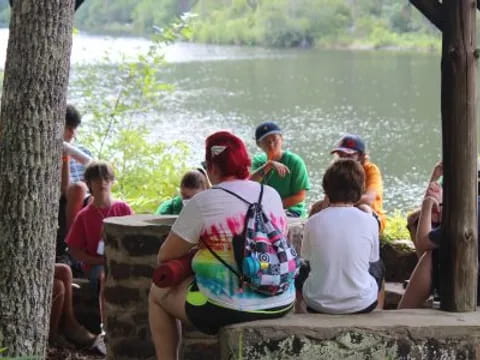 a group of people sitting on a bench by a lake