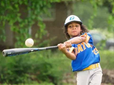 a young girl swinging a baseball bat