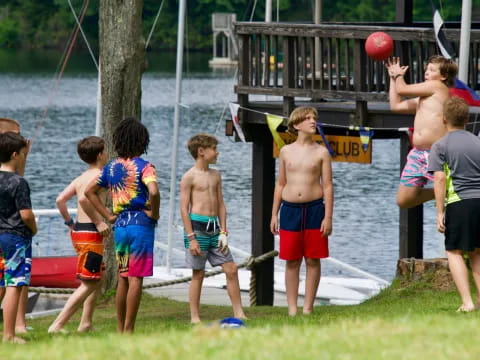 a group of kids playing with a ball by a lake
