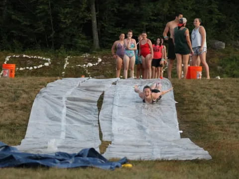 a group of people standing around a person lying in a large white tent