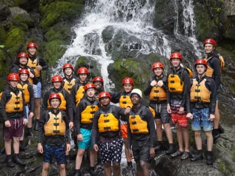 a group of people posing for a photo in front of a waterfall