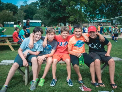 a group of boys sitting on a bench in a park