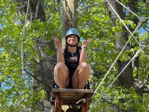 a person wearing a helmet and sitting on a wooden structure in the woods