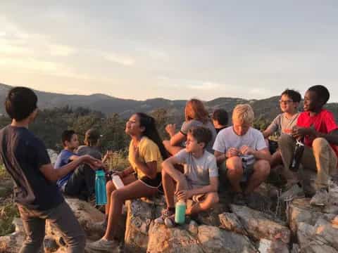 a group of people sitting on a rock ledge overlooking a valley