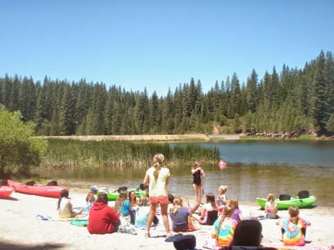 a group of people sitting on a beach by a lake