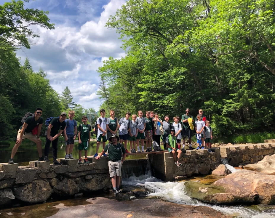 a group of people standing on rocks by a river