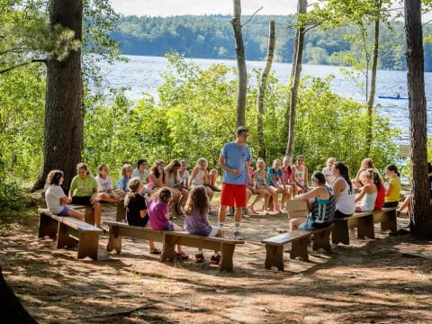 a group of people sitting on picnic tables by a lake